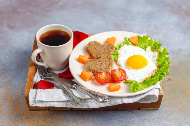 Desayuno el día de San Valentín: huevos fritos y pan en forma de corazón y verduras frescas.