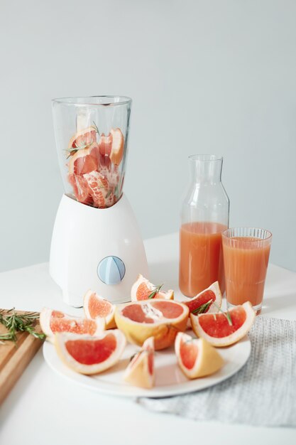 Desayuno de dieta saludable fitness sobre pared blanca. Trozos de pomelo y romero en la licuadora. Batido refrescante desintoxicante.