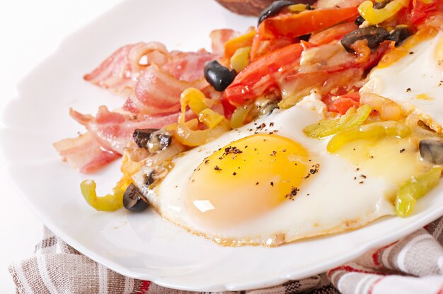 Desayuno: huevos fritos con tocino, tomates, aceitunas y lonchas de queso.