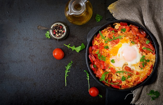 Desayuno. Huevos fritos con verduras. Shakshuka en una sartén sobre un negro en el estilo turco.