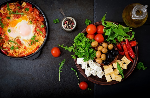 Desayuno. Huevos fritos con verduras. Shakshuka en una sartén sobre un negro en el estilo turco.