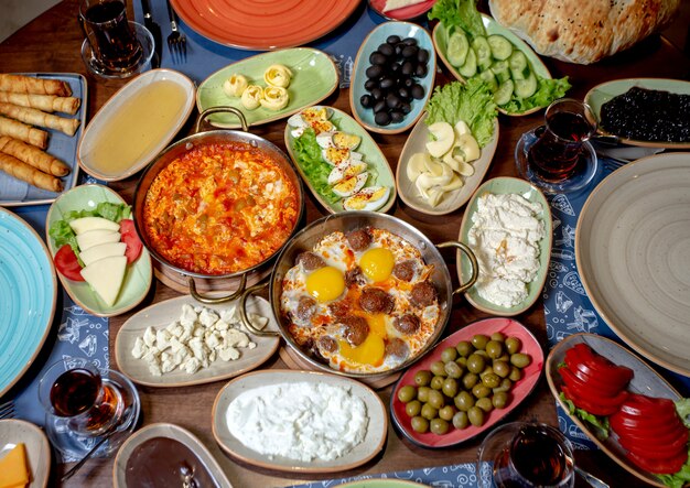 Desayuno con huevos revueltos, aceitunas, queso blanco, pepinos, tomates y té.