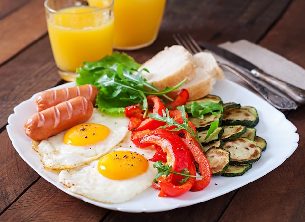 Desayuno inglés: huevos fritos, salchichas, calabacín y pimientos