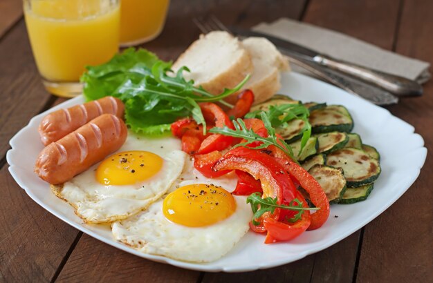 Desayuno inglés: huevos fritos, salchichas, calabacín y pimientos