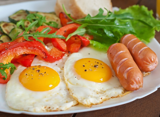 Foto gratuita desayuno inglés: huevos fritos, salchichas, calabacín y pimientos