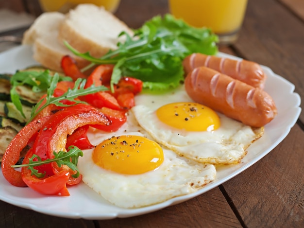 Desayuno inglés: huevos fritos, salchichas, calabacín y pimientos