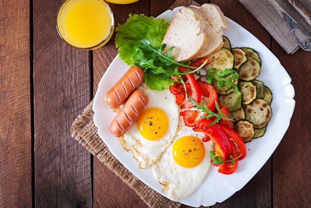 Desayuno inglés: huevos fritos, salchichas, calabacín y pimientos