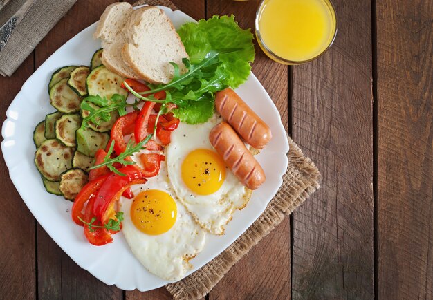 Desayuno inglés: huevos fritos, salchichas, calabacín y pimientos