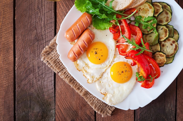 Desayuno inglés: huevos fritos, salchichas, calabacín y pimientos