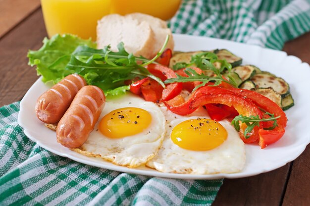 Desayuno inglés: huevos fritos, salchichas, calabacín y pimientos