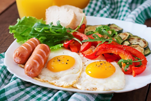 Desayuno inglés: huevos fritos, salchichas, calabacín y pimientos