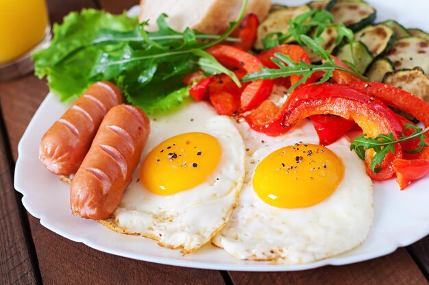 Desayuno inglés: huevos fritos, salchichas, calabacín y pimientos