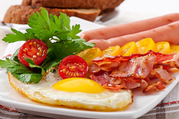 Desayuno inglés: huevos fritos, tocino, salchichas y pan de centeno tostado