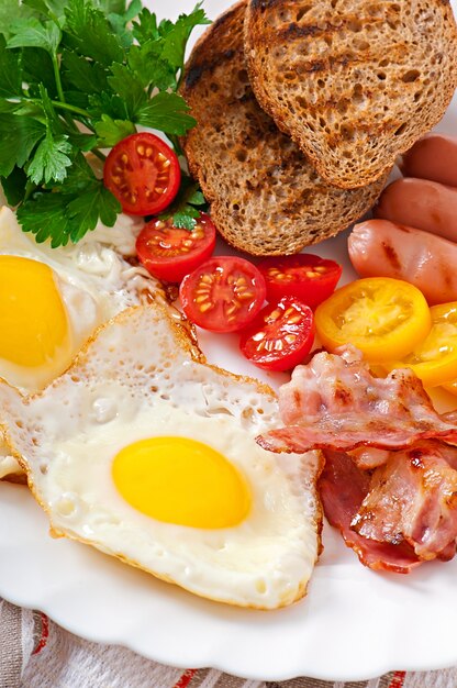 Desayuno inglés: huevos fritos, tocino, salchichas y pan de centeno tostado