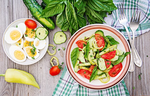 Desayuno en el jardín de verano. Ensalada de tomates y pepinos con cebolla verde y albahaca.