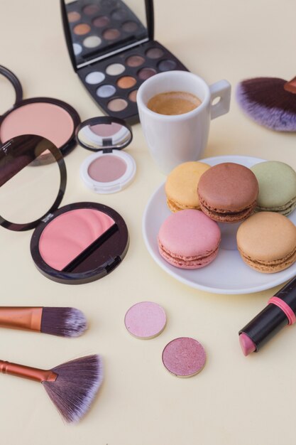 Desayuno de macarrones con producto de café y cosméticos sobre fondo beige