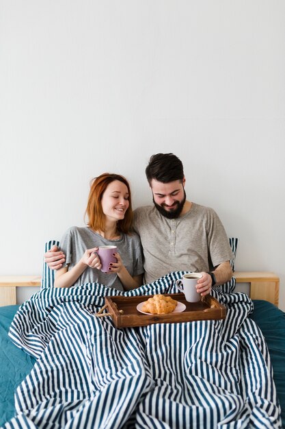 Desayuno de la mañana en la cama y pareja sonriente