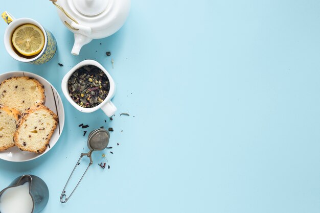 Desayuno de la mañana con hierbas y colador de té sobre fondo coloreado