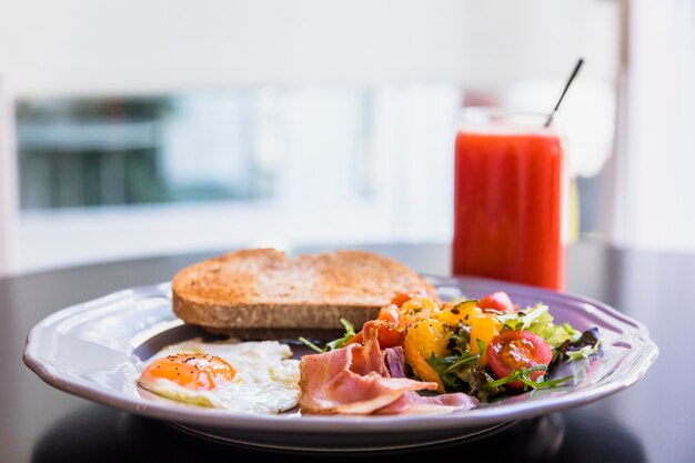 Desayuno en plato gris con batido en mesa negro.