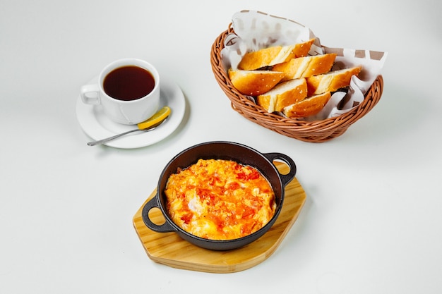 Desayuno preparado con huevo y tomate, té negro y pan