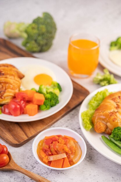 Desayuno que consiste en pan, huevos fritos, brócoli, zanahorias, tomates y lechuga en un plato blanco.