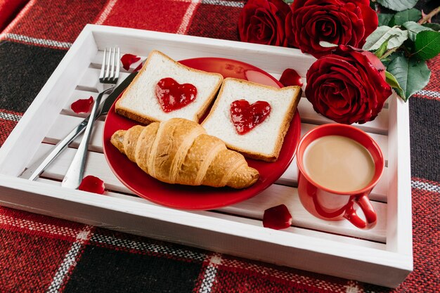 Desayuno romántico en bandeja sobre mesa.