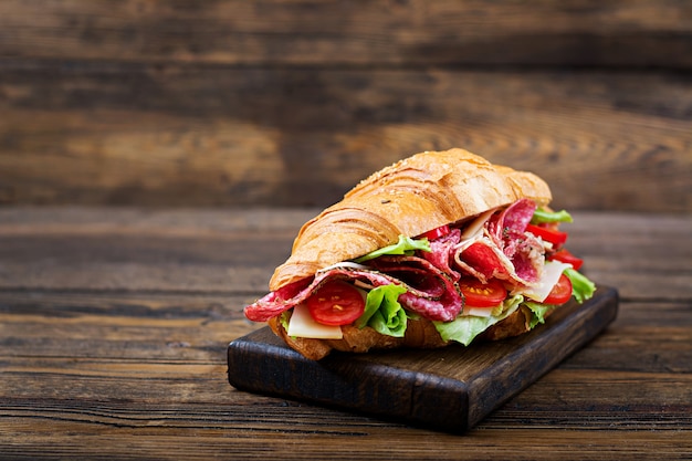 Desayuno sabroso Croissant apetitoso con salami y queso y tomates