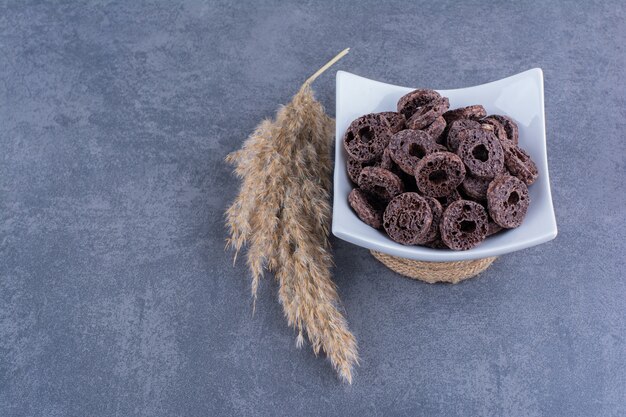 Desayuno saludable con aros de maíz chocolate en un plato sobre piedra.