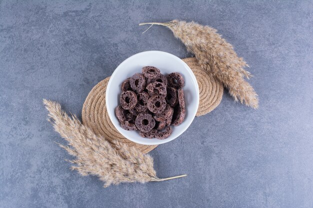 Desayuno saludable con aros de maíz chocolate en un plato sobre piedra.