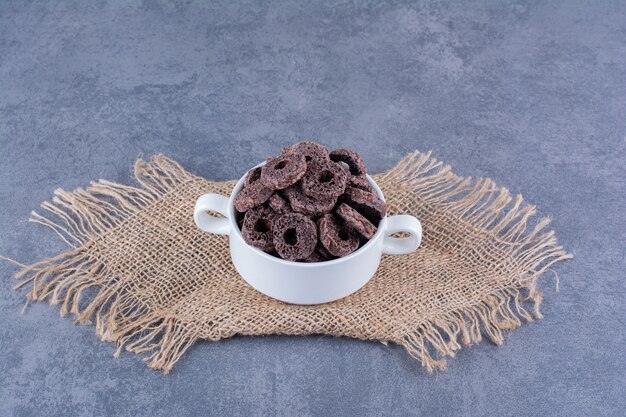 Desayuno saludable con aros de maíz chocolate en un plato sobre piedra.