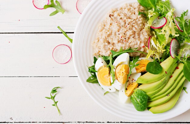 Desayuno saludable. Menú dietético Gachas de avena y ensalada de aguacate y huevos. Vista superior