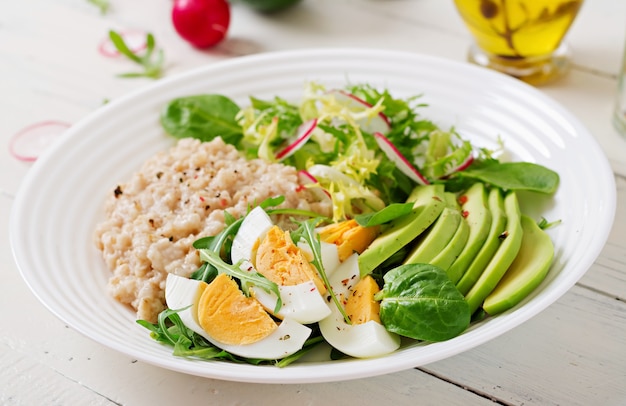 Desayuno saludable. Menú dietético Gachas de avena y ensalada de aguacate y huevos.
