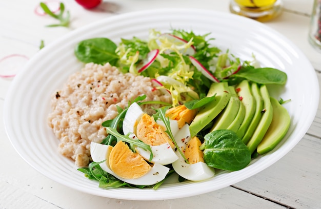 Desayuno saludable. Menú dietético Gachas de avena y ensalada de aguacate y huevos.