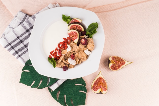 Desayuno saludable en plato con hojas de monstera falsas; rodajas de higo y servilleta de cocina