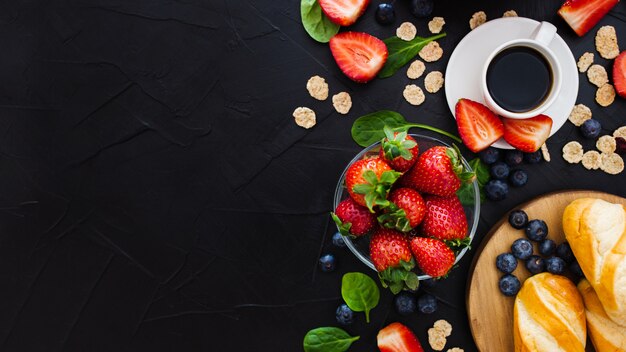 Desayuno saludable sobre un fondo negro de madera. Vista superior. Espacio libre para tu texto.