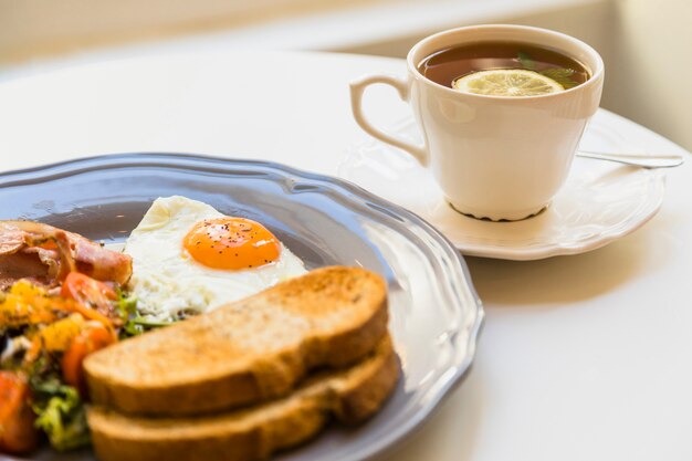 Desayuno saludable y taza de té en mesa blanca