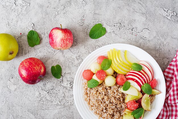 Desayuno saludable. Trigo sarraceno o gachas de avena con melón fresco, sandía, manzana y pera. Comida sabrosa. Vista superior, espacio de copia, plano