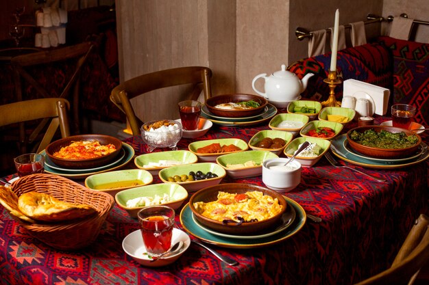 Desayuno tradicional con huevos y té negro, queso, mantequilla, miel, pepino, tomate y mermeladas.