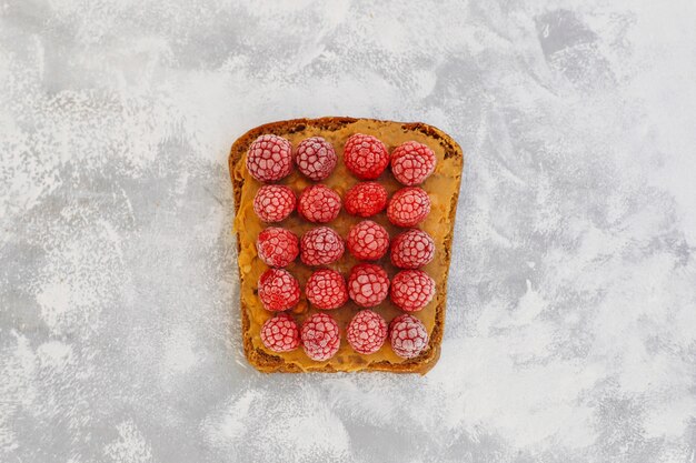 Desayuno tradicional de verano americano y europeo: sándwiches de pan tostado con mantequilla de maní, bayas, duraznos, higos, fresas, frambuesas, copia vista superior