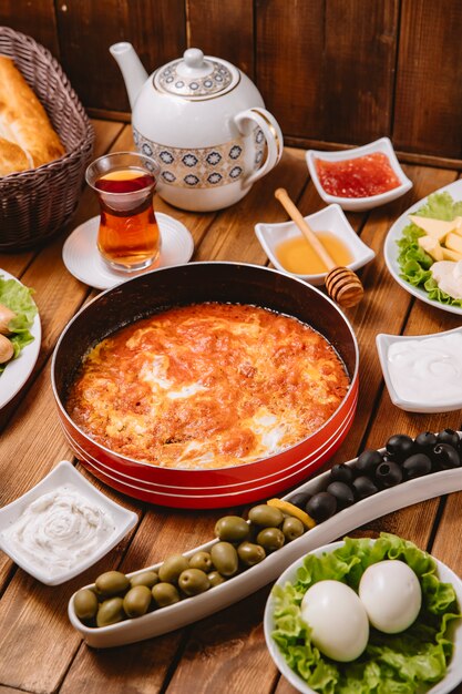 Desayuno turco con huevo y tomate, salchichas, aceitunas, huevos y té