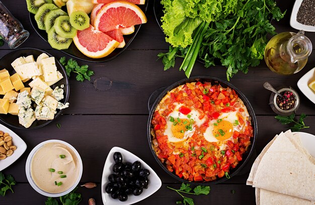 Desayuno turco .shakshuka, aceitunas, queso y fruta.