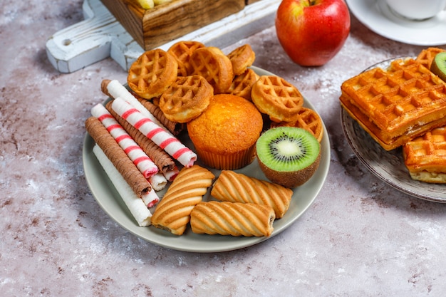 Desayuno con varios dulces, obleas, hojuelas de maíz y una taza de café.