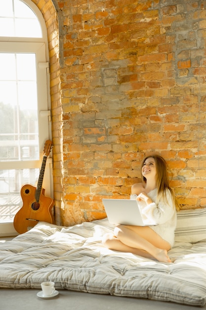 Descansando en casa. Hermosa mujer joven acostada sobre un colchón con luz solar cálida.