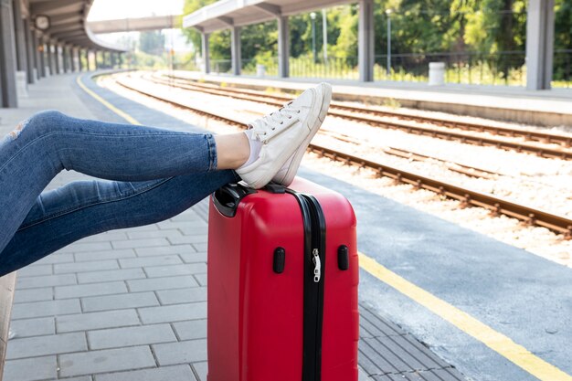 Descansando las piernas sobre el equipaje en la estación de tren