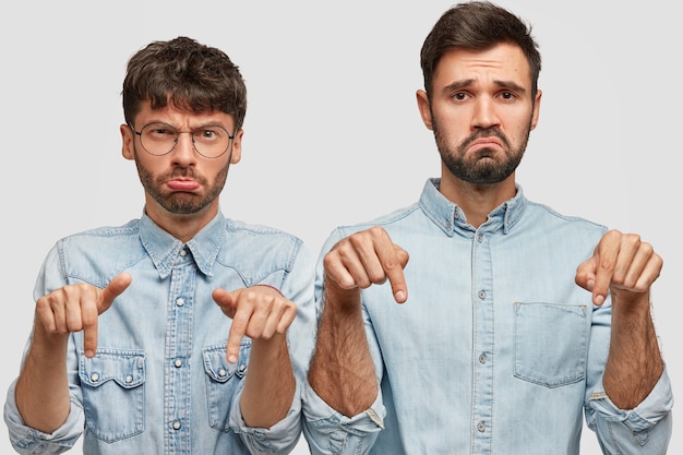 Descontento dos hermanos tienen expresiones hoscas, mantienen los dedos índices bajos, usan camisas de mezclilla, se sienten disgustados