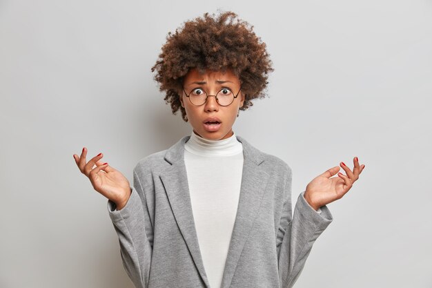 Descontento insatisfecho joven con cabello afro rizado se extiende palmas hacia los lados