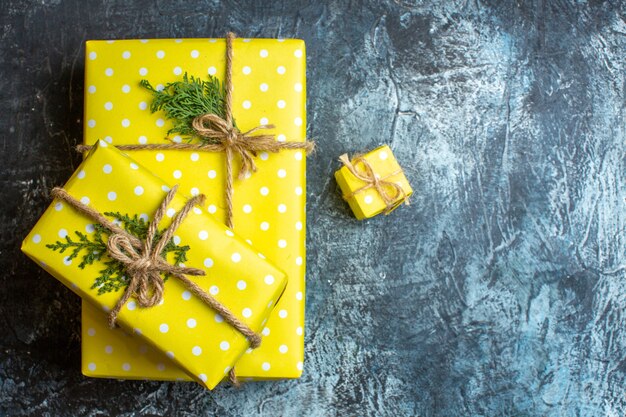 Descripción general de hermosas cajas de regalo de Navidad amarillas apiladas para miembros de la familia sobre fondo oscuro