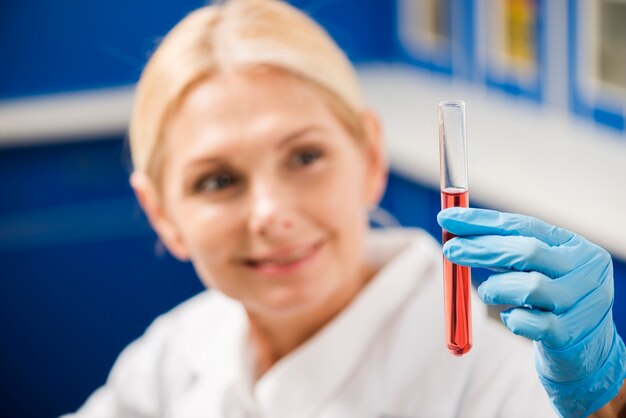 Desenfocada sonriente mujer científico sosteniendo objeto de laboratorio