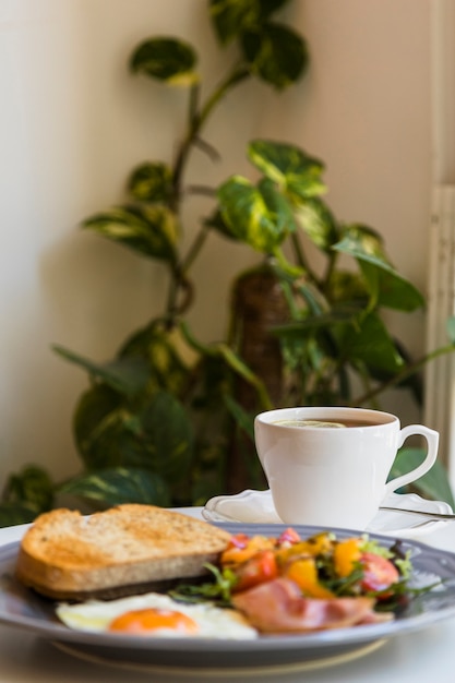Desenfoque de desayuno y té en la mesa frente a las plantas