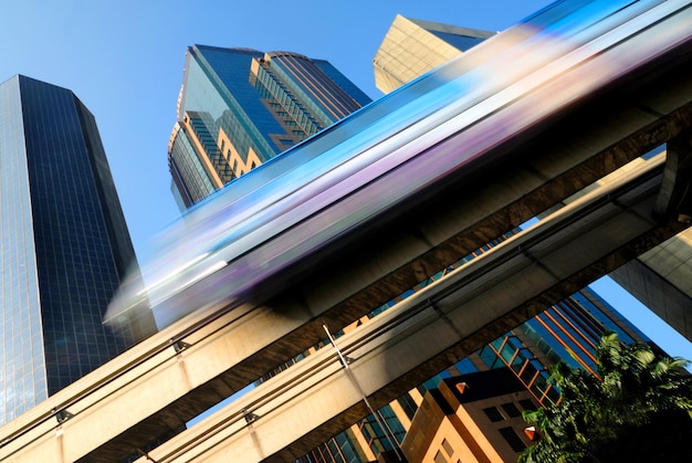 Desenfoque de movimiento de un skytrain acelerando a través de un moderno distrito de negocios